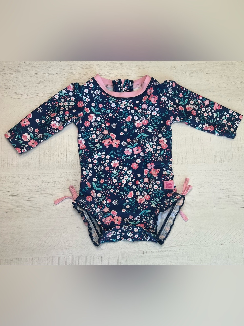 RuffleButts Baby Girl Navy Floral Long Sleeve Swimsuit with Pink Trim